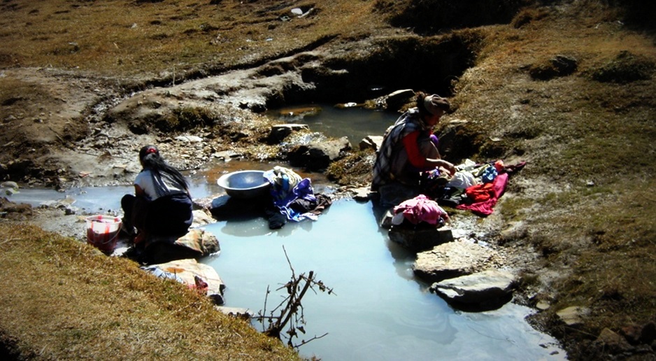 Women handwash their clothing at a nearby water source